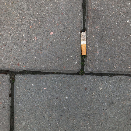 Fimp som ligger nertrampad på trottoaren